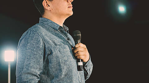 a photo of a middle aged white mail standing patriotically while holding a microphone